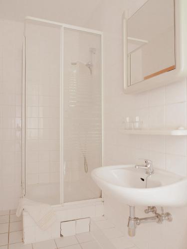 a white bathroom with a sink and a shower at Hotel zur Sonne in Cottbus
