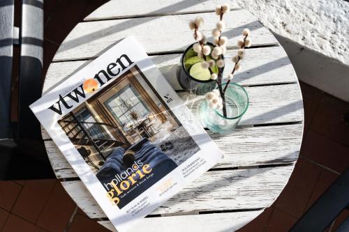 a newspaper on a table with a magazine and a plant at Hello Noordwijk - Appartement Duindamseweg 14E in Noordwijk aan Zee