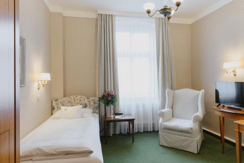 a hotel room with a bed and a chair and a television at Romantik Hotel zur Post in Fürstenfeldbruck