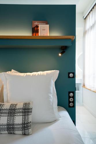 a bedroom with a blue wall and a white bed at L'INVITATION AU VOYAGE - Hôtel & Spa in Honfleur