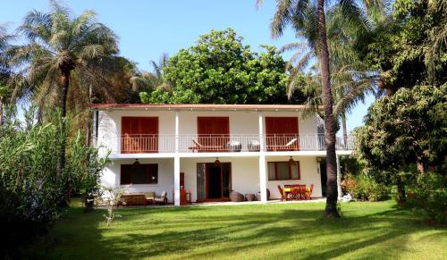 a white house with palm trees in the yard at Évasion au Cap Skirring in Cap Skirring