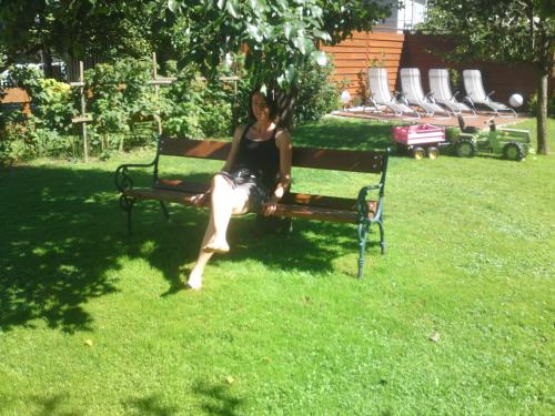 a woman sitting on a park bench in the grass at Appartements Schweiberer in Ried im Zillertal