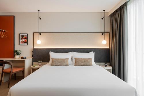 a bedroom with a large white bed and a desk at Citadines Tanjung Tokong Penang in George Town
