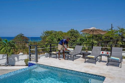 a man standing next to a pool with a table and chairs at Hospitality Expert CB All Pool Beach in Montego Bay