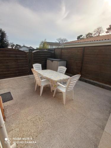 une table blanche et des chaises sur une terrasse dans l'établissement Maison à 600 m de la plage, à Saint-Georges-de-Didonne