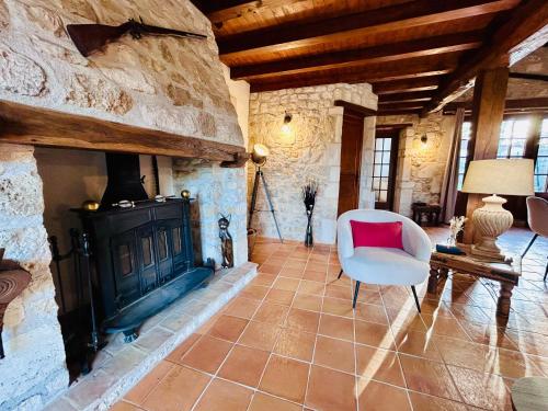 a living room with a fireplace and a chair at L'Envol - Spacieuse maison avec piscine privative in Champagne