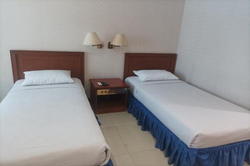 a room with two beds and a nightstand between them at Hotel Efita in Kamparganya