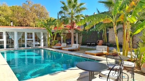 una piscina con mesas y sillas junto a una casa en Jardin d'Azur Alaçatı, en Alacati