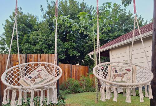 two swinging chairs in a yard next to a fence at Tree Living in Krugersdorp