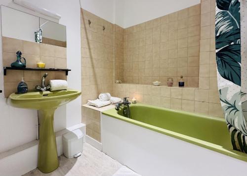 La salle de bains est pourvue d'un lavabo vert et d'une baignoire. dans l'établissement Panorama Fondaudege, à Bordeaux