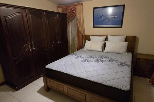 a bedroom with a bed and a wooden cabinet at Mauritian Home in the country in Lalmatie