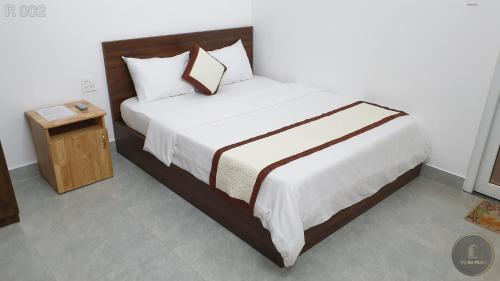 a bedroom with a large bed with a night stand at Vy An Hotel in Bao Loc