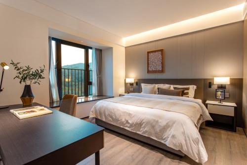 a bedroom with a bed and a desk and a window at Ascott Fengyishan Shenzhen in Shenzhen