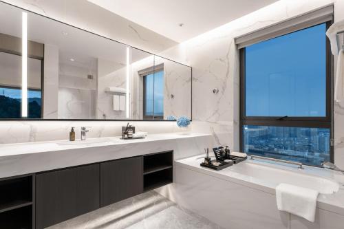 a bathroom with two sinks and a large mirror at Ascott Fengyishan Shenzhen in Shenzhen