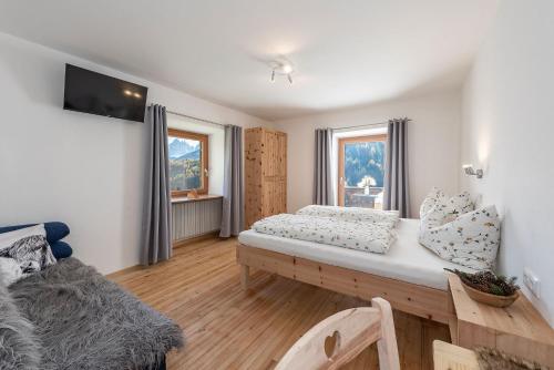 a bedroom with a bed and a couch and two windows at Austillerhof - Urlaub auf dem Bauernhof in Funes