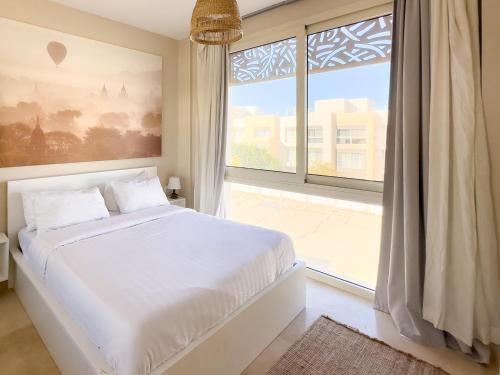 a bedroom with a white bed and a large window at El Gouna - BIRD NEST in Hurghada