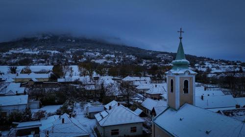 a church with a steeple and snow covered roofs at CsillaG Apartman in Kisapáti
