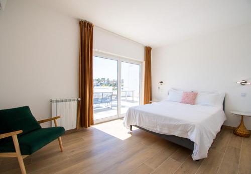 une chambre avec un lit, une chaise et une fenêtre dans l'établissement Casa Cubo - Amazing Central 6 bedroom Villa, à Carvoeiro