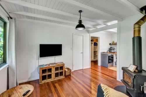 a living room with a flat screen tv on a white wall at Lumeah by the Creek in Whian Whian