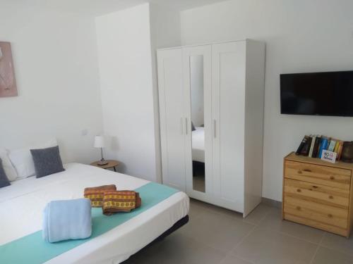 a bedroom with a bed and a dresser with a television at Yumbo Rainbow Homes D in Maspalomas