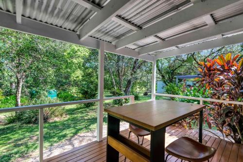 a screened porch with a wooden table and chairs at Lumeah by the Creek in Whian Whian