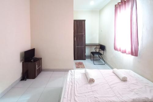 a white bedroom with a bed and a television at D Cost 19 Syariah Mitra RedDoorz in Palas 2