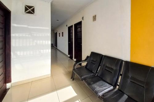 a waiting room with a black leather chair in a hallway at D Cost 19 Syariah Mitra RedDoorz in Palas 2