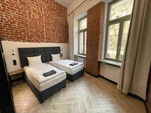 a bedroom with two beds and a brick wall at Pod Błękitnymi Podkowami in Wrocław