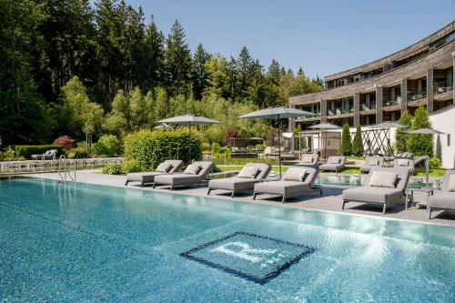 a swimming pool with lounge chairs and a hotel at Wellness & Naturresort Reischlhof in Wegscheid