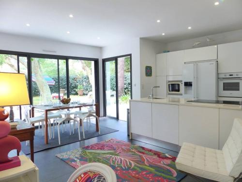 une cuisine avec des armoires blanches et une table avec des chaises dans l'établissement Villa les chardonnerets entre Lac et Océan pour 10-12 personnes, à Hossegor