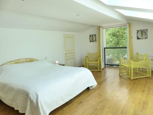 une chambre avec un lit et deux chaises et une fenêtre dans l'établissement Villa les chardonnerets entre Lac et Océan pour 10-12 personnes, à Hossegor