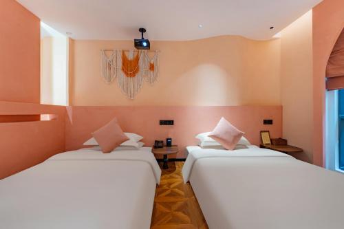 two beds in a room with orange walls at Chaozhou Fanhuali B&B in Chaozhou