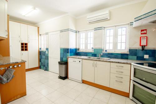 a kitchen with white cabinets and blue and white tiles at Casa Filipa Full house - Spacious Villa with Private Pool & Jacuzzi in Praia do Carvoeiro
