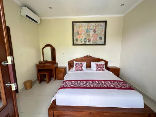a bedroom with a bed and a picture on the wall at Brata Cottage Ubud in Ubud