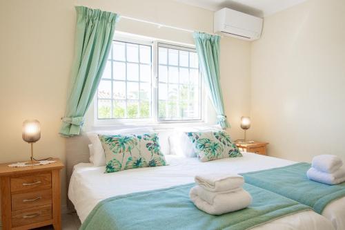 a bedroom with a bed with blue curtains and a window at Casa Filipa Full house - Spacious Villa with Private Pool & Jacuzzi in Praia do Carvoeiro