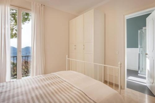 a white bedroom with a bed and a large window at Villa Rosa del Garda Golf and Bike in Garda
