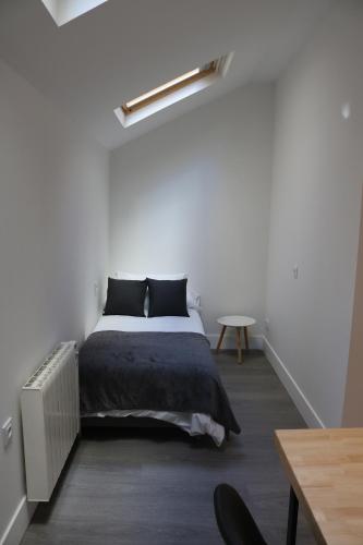 a white bedroom with a bed and a table at Apartamento en Ferrol in Ferrol