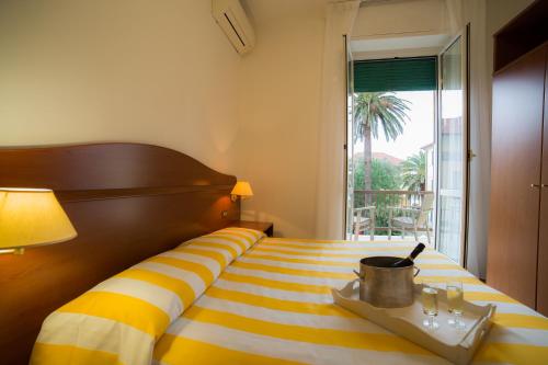 ヴァラッツェにあるHotel Villa Gloriaの黄色と白のストライプのベッドが備わるホテルルームです。