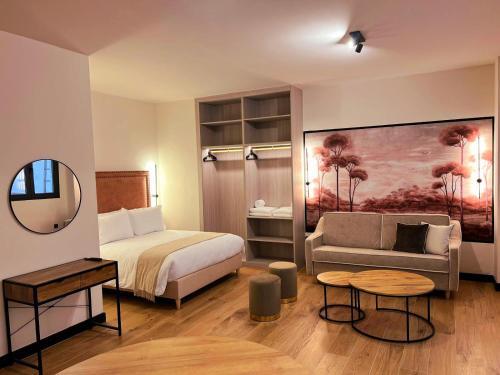 a bedroom with a bed and a couch and a mirror at Hotel Aptos Alejandra Home by Maxi Hoteles in Granada