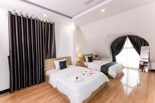 a bedroom with two beds and a large window at Hawaii Hotel Dalat in Da Lat