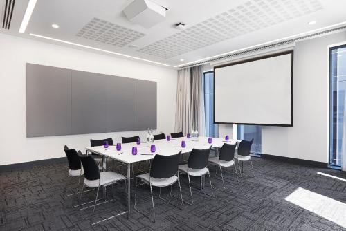 a conference room with a table and chairs and a screen at INNSiDE by Meliá Manchester in Manchester