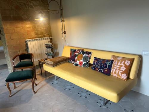a yellow couch with pillows and a chair in a room at Morelliana4Rooms in Scansano