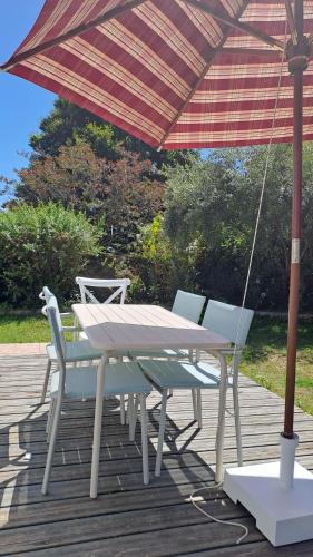 une table et des chaises sous un parasol sur une terrasse dans l'établissement le chalet de laura, à Pornic