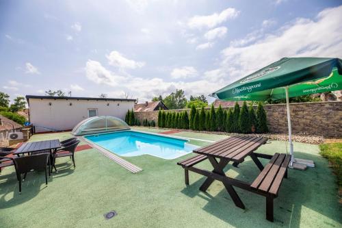 a swimming pool with two picnic tables and an umbrella at Chalupa Dešná in Dešná
