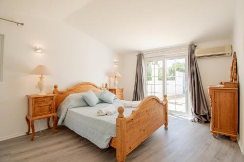 ein Schlafzimmer mit einem Holzbett und einem Fenster in der Unterkunft The Gaff - Great 5-Bedroom Villa in Poço Partido