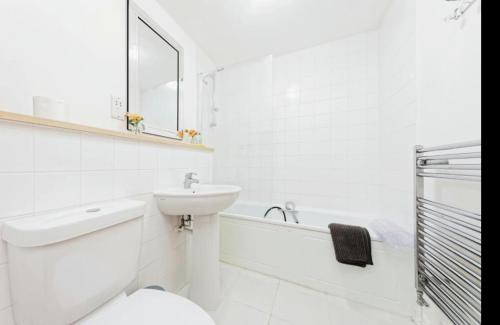 a white bathroom with a sink and a toilet and a tub at Beautiful Family Town Home With Private Parking in Canterbury