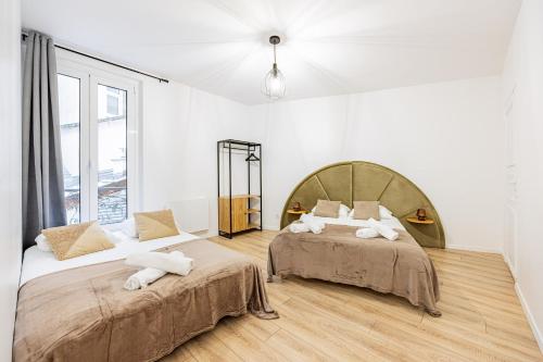 twee bedden in een kamer met witte muren en houten vloeren bij Nation Confort & Espace in Parijs