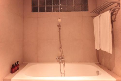 a bath tub with a shower in a bathroom at Amaya Residence Jimbaran in Jimbaran