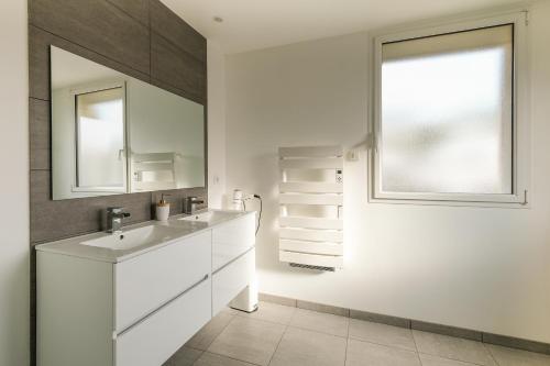 une salle de bain blanche avec un lavabo et une fenêtre dans l'établissement Côté Océan - Appt vue mer de 134 m2, à Saint-Nazaire