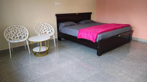 ein Schlafzimmer mit einem Bett und zwei Stühlen in der Unterkunft Roopa Resorts in Araku